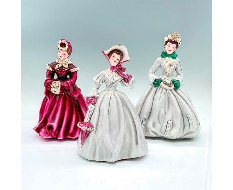 3 vintage figures of young ladies in dress. Delia in a dark magenta with white and gilded accents. Louise in a gray dress wit