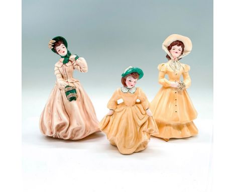 3 vintage figures of young ladies in dresses. Clarissa in a beige gown with green and gilded accents. Joy in a yellow dress a