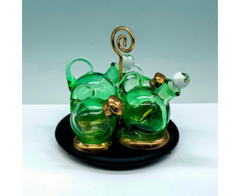 A set of 4 green glass serving items that consist of 2 seasoning shakers and 2 oil and vinegar containers with a black metal 