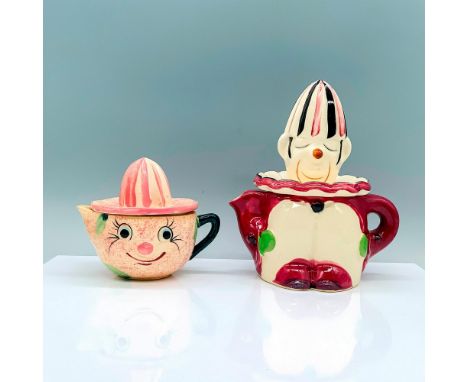 2 citrus juicers designed around a clown theme, one is a smiling face design with pink and green coloration, the other is a s