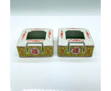 Two ceramic ashtrays with a slot for matches. They are decorated with a red and yellow floral motif and Chinese writing. Dime