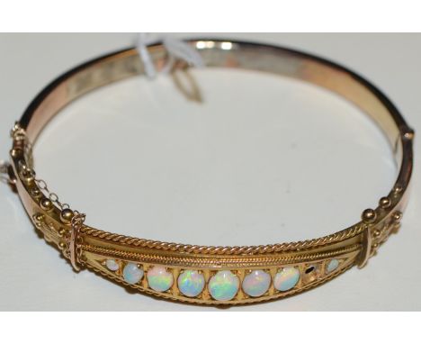 An Edwardian style Gilson opal hinge bangle, inset with nine graduated free form opaline stones, flashing vibrant green, viol