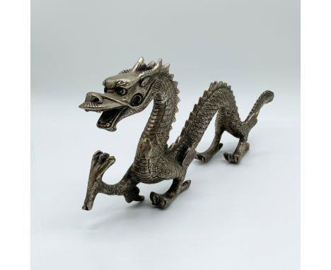 A cast metal dragon figurine featuring intricate scales, a fierce expression, and a curved body. This detailed piece symboliz