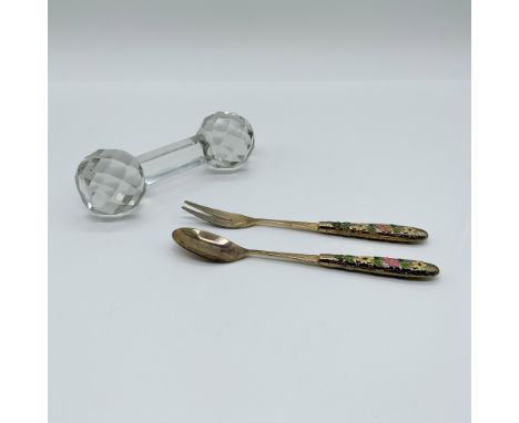 This lot features a crystal knife rest and a pair of gold-plated utensils with intricate floral handles. The knife rest showc