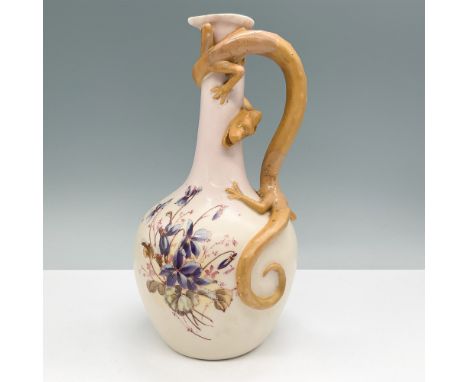 An antique ceramic pitcher featuring a striking dragon handle design, standing 9.5"H. This unique piece is adorned with intri