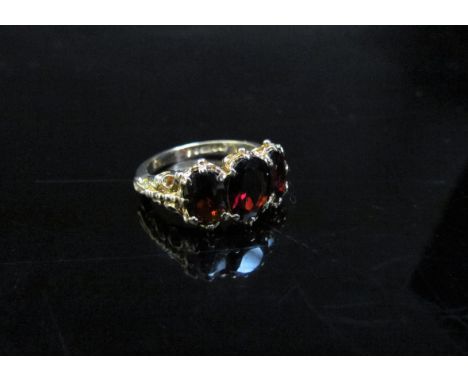 A 9ct gold ring set with three garnets in ornate shoulders. Size L/M, 4g 