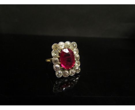 A synthetic ruby and diamond ring, the central oval ruby 11 x 9mm framed by 14 x 0.20ct approx diamonds in rectangular settin