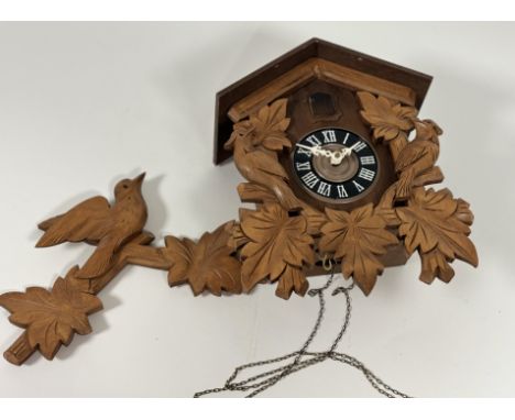 A Mid 20thc German Chalet Style cuckoo clock with bird and leaf carved decoration with roman numeral dial, with chains, and t