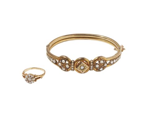 An Edwardian diamond and pearl set bangleof hinged design, claw set with a central old round cut diamond in a shaped surround