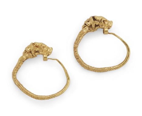 A pair of Hellenistic gold earrings, with bull head terminals, the tapering coiled wire hooking through the loop under the bu