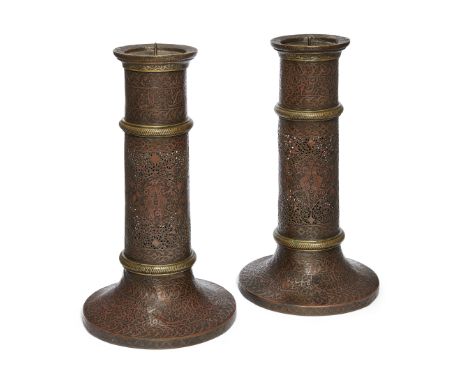 A pair of Qajar brass openwork candlesticks, Persia, 19th century, each on a spreading foot and rising in sections,&nbsp;pier