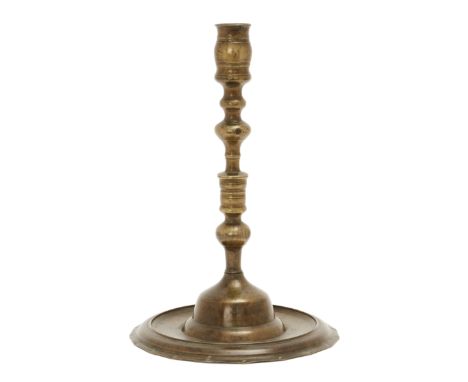 An Ottoman spun brass candlestick, Turkey, 17th century, made in two sections, on wide flattened foot with upturned rim, a se