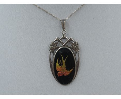 A silver and enamel pendant by Charles Horner having an iridescent yellow and orange swallow on black background in decorativ