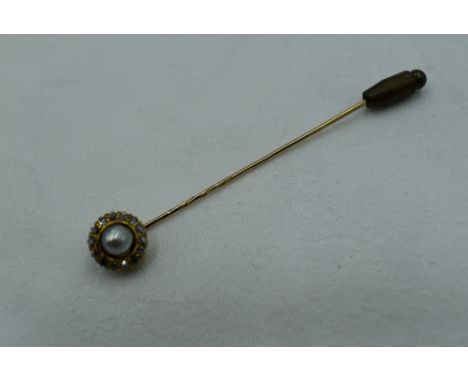 A yellow metal stick pin having a split pearl and diamond chip cluster, approx 2.9g