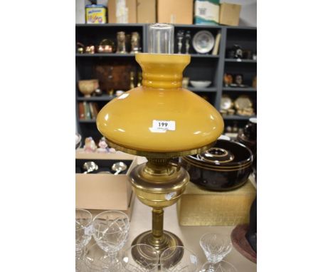 A vintage brass effect and glass paraffin lamp with broad orange/brown glass shade