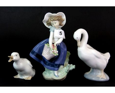 A Lladro figure of a girl and two Nao geese.