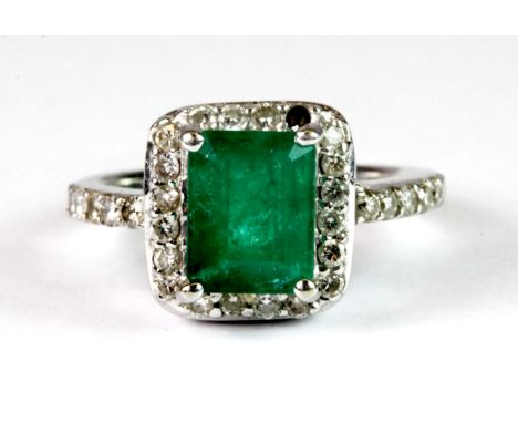 14 ct white gold ring (stamped 14k) set with and emerald surrounded by diamonds. M. Approx 6 grams. Please note this lot is a