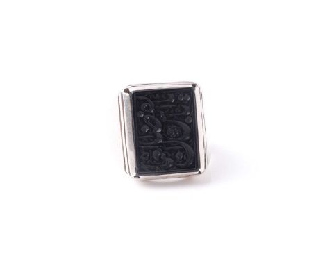 An Eastern white metal and black onyx gentleman's ring, the rectangular stone with intaglio cut Islamic calligraphy, the ston