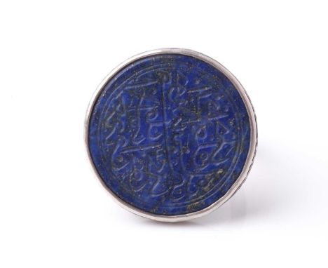 A probably Persian white metal dress ring set with a circular lapis lazuli panel engraved with Islamic calligraphy. 2.2 cm di