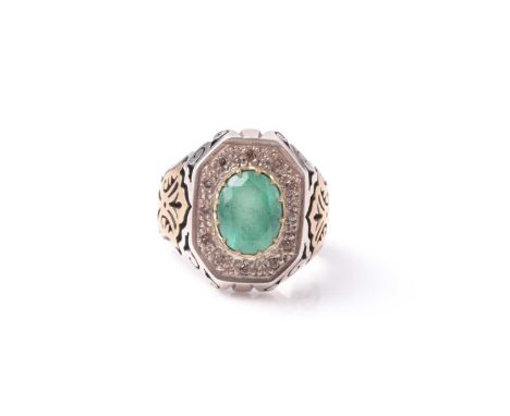 A heavy white metal gentleman's ring set with a claw set oval cut emerald within a border of small diamonds in a gilt metal s