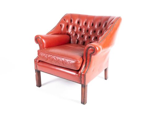 A 20th-century red deep button upholstered 'Chesterfield' armchair with close nailed detail and fitted loose cushion, on squa