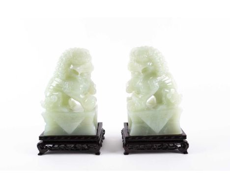 A pair of Chinese carved pale green Jadeite figures of "Dogs of Fo", 20th century. On mock cloth draped rectangular socles. W