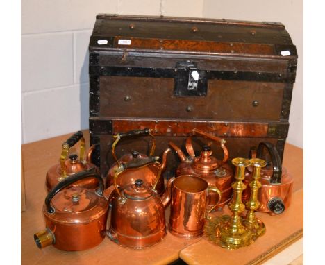 A wooden and metal bound dome-topped travelling trunk containing a small group of copper including kettles 