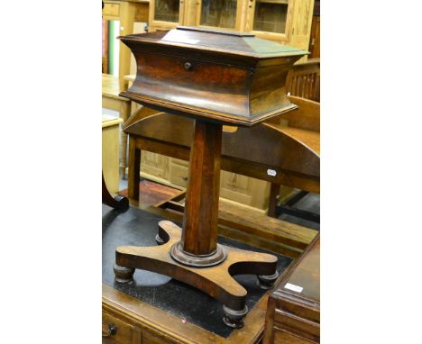 A regency rosewood sarcophagus form tea caddy, raised on a tapering faceted standard and a waisted etch form platform base 