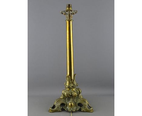 A CIRCA 1900 BRASS TABLE LAMP and tasselled shade, the capped circular column with pierced Rococo style base, 51.5 cms high i