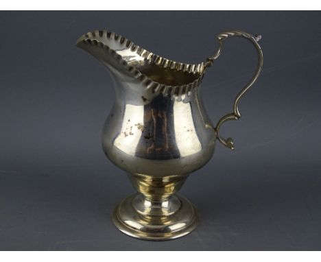 A HELMET SHAPED SILVER CREAM JUG on pedestal base with scroll handle, Chester 1920 (crease to the spout), 3 troy ozs