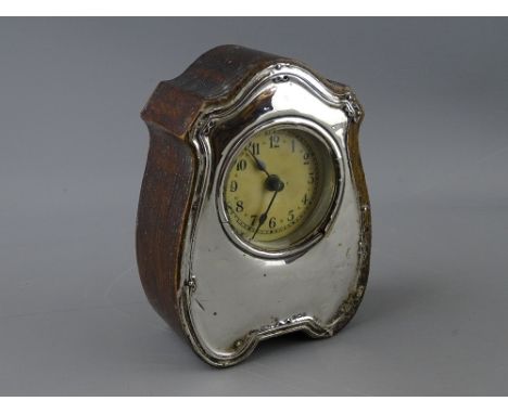 A WOODEN ENCASED MANTEL CLOCK, the shaped front around the circular dial in silver, Birmingham 1944