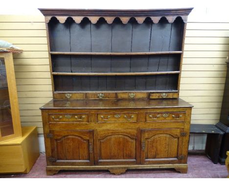 A GEORGE III OAK &amp; ELM SPICE DRAWER NORTH WALES DRESSER, the three shelf rack with decorative canopy frieze and four long