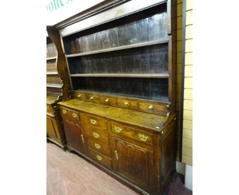 A GEORGE III NORTH WALES OAK SPICE DRAWER DRESSER, the three shelf wide boarded rack having five lower drawers over a base ar
