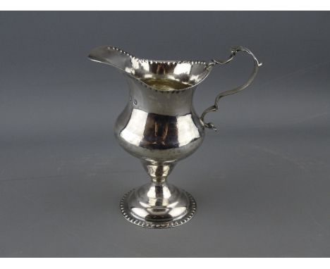 A GEORGE IV SILVER HELMET SHAPED PEDESTAL CREAM JUG with beaded foot and rim decoration, London 1823, 2.7 troy ozs, 12 cms hi