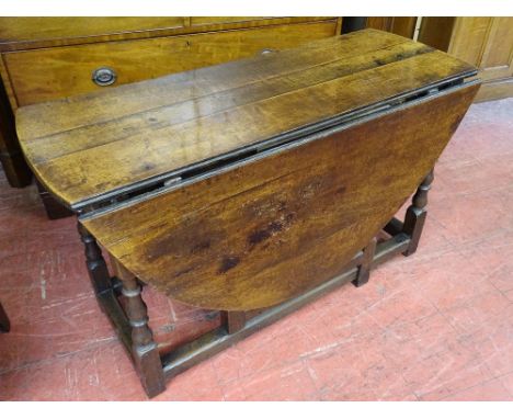 AN OAK TWIN FLAP GATE LEG DINING TABLE with single end drawer in the antique style on turned and block supports with block st