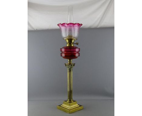 A VICTORIAN CORINTHIAN COLUMN BRASS OIL LAMP with cranberry font and tinted shade, 82 cms high overall