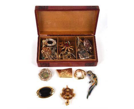 Red jewellery box containing a group of vintage brooches, including a heart shaped Monet brooch with other brooches, a gem se
