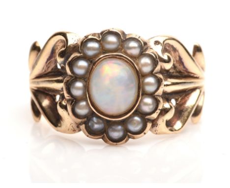 Opal and pearl ring, central oval opal with a surround of seed pearls with foliate motif shoulders, in tested 9 ct, size ICon