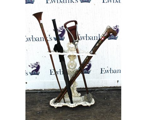 A Victorian cast iron stick stand, painted white, 65cm high, containing a selection of walking sticks, a copper hunting horn,