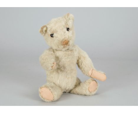 A British 1930s teddy bear cub,  with beige wool plush, clear and black glass eyes with remains of brown painted backs, light