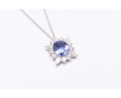 A sapphire and diamond cluster pendant, designed as a central oval mixed cut sapphire claw set within a shaped border of thir