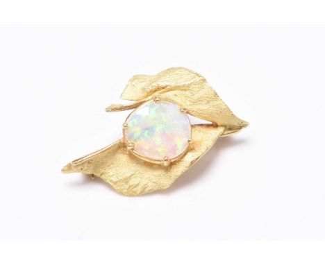 An opal set brooch, the central irregular shaped opal claw set within two yellow metal stylised ‘leaves’ with textured finish