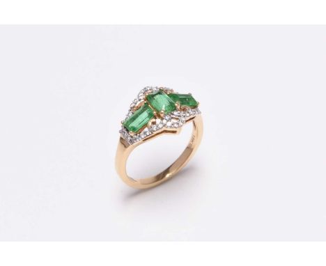An 18ct gold emerald and diamond ring, designed as three rectangular cut emeralds claw set within scrolling diamond set mount