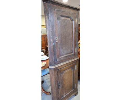 A Georgian oak corner cupboard enclosed two panelled doors, on bracket feet, 27" wide