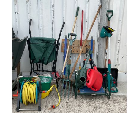 A collection of garden tools, to include forks, rakes, folding wheelbarrow, hose, watering cans, a garden seat, a work bench 