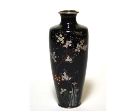 A cloisonne enamel vase with foliage and bird decoration on a dark blue background 