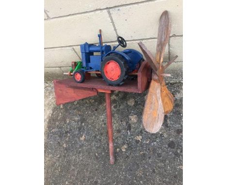 A wooden weather vane in the form of a Fordson tractor with rear propeller.