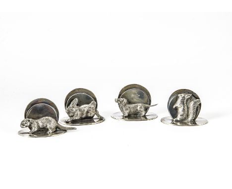 A set of four George V silver menu holders by G.B & Co Ltd, oval bases with an otter, squirrel, small dog and a rabbit suppor