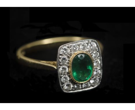 An emerald and diamond set dress ring, the tablet top with oval mixed cut emerald within a colette setting surrounded by bril