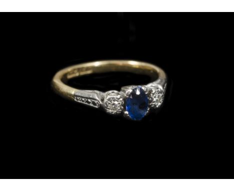 A sapphire and diamond 18ct gold and platinum set three stone ring, oval mixed cut sapphire flanked by two illusion set eight